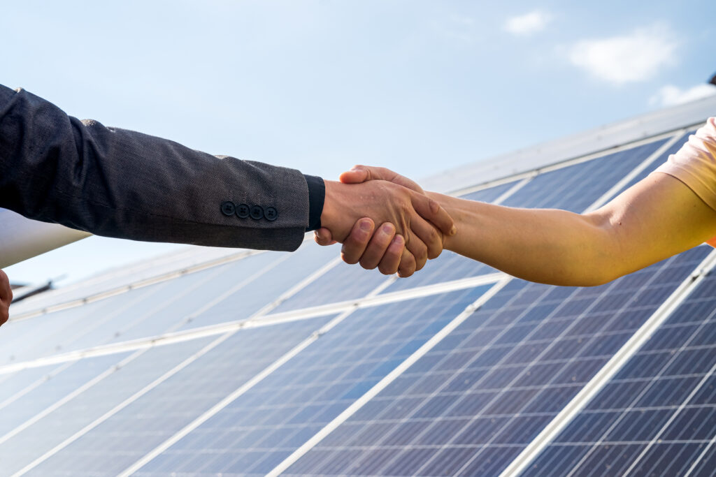 shaking hands against solar panel after the conclusion of the agreement in the renewable energy